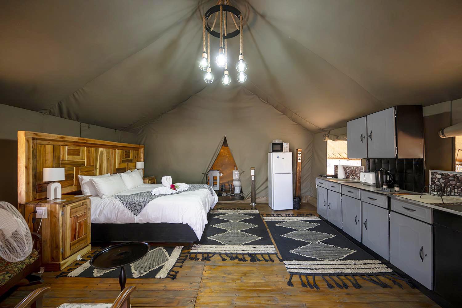 Offener Glamping-Innenraum mit Bett und Küche